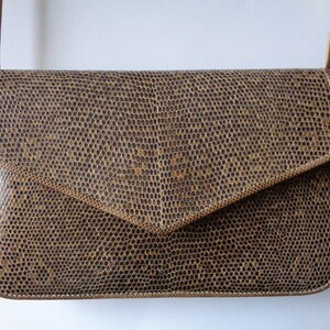 May include: A brown leather shoulder bag with a snakeskin pattern. The bag has a flap closure and a long strap.