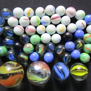 Op de afbeelding: Een verzameling kleurrijke glazen knikkers met verschillende patronen en swirls. De knikkers zijn voornamelijk wit, blauw, groen en rood.