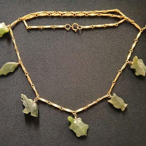 May include: A gold chain necklace with green jade pendants shaped like fish, turtles, and elephants.