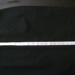 May include: A black skirt with a seam down the front. The skirt is measured with a tape measure that reads 22 inches.