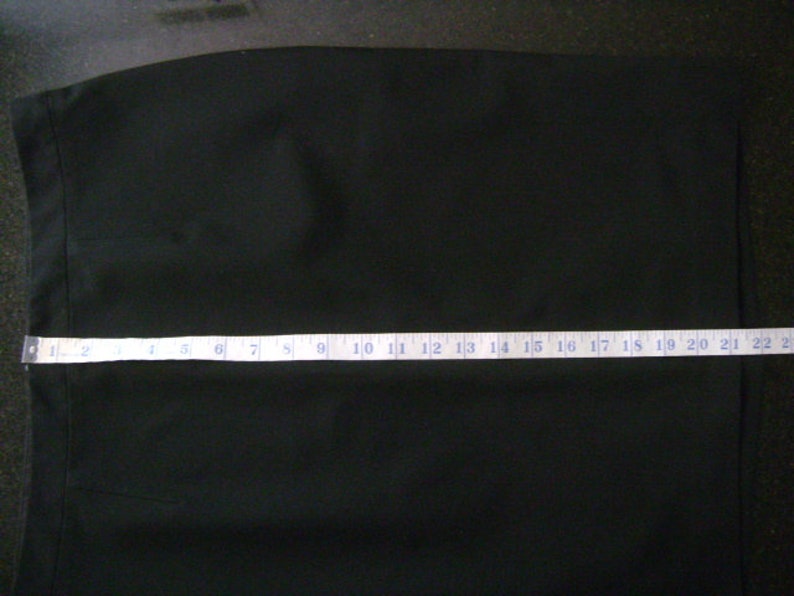 May include: A black skirt with a seam down the front. The skirt is measured with a tape measure that reads 22 inches.