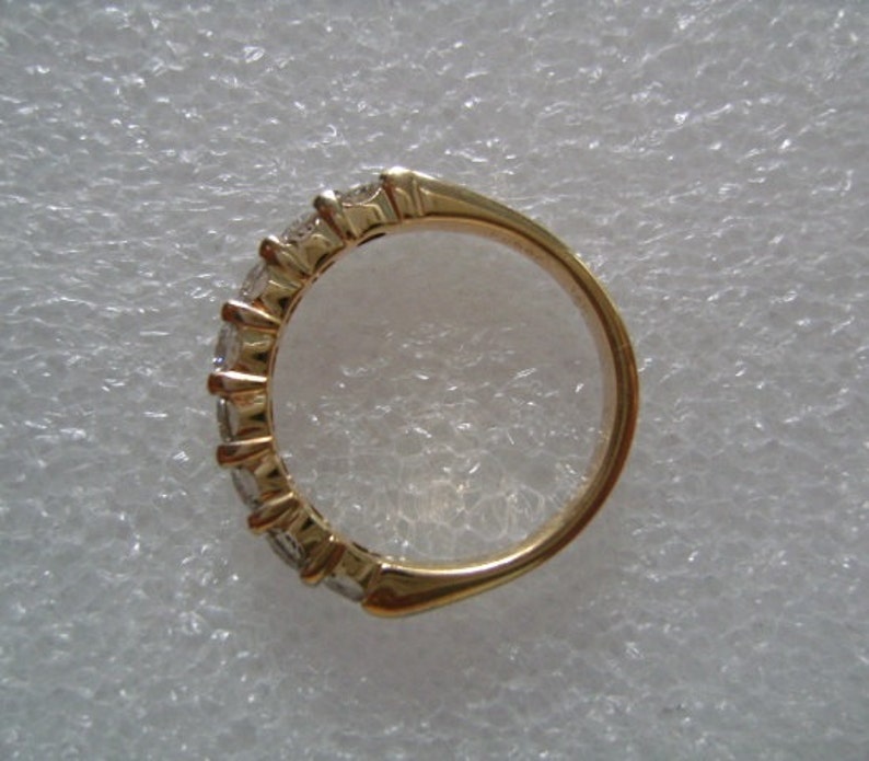 May include: A gold band ring with a row of clear gemstones set in the band.
