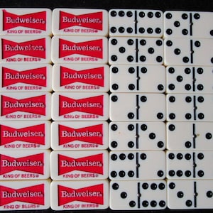 May include: A set of dominoes with white tiles and black dots. The dominoes are arranged in a grid pattern. The dominoes are surrounded by red and white Budweiser beer labels.