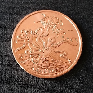 May include: A copper-colored coin featuring a detailed depiction of a kraken attacking a Viking ship. The kraken's tentacles wrap around the ship, with the word "KRAKEN" inscribed below. The coin is set against a dark background.