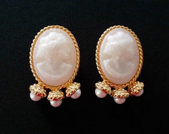 May include: A pair of gold tone earrings with a cameo design and pearl accents.