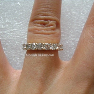 May include: A gold band ring with a row of clear cubic zirconia stones.