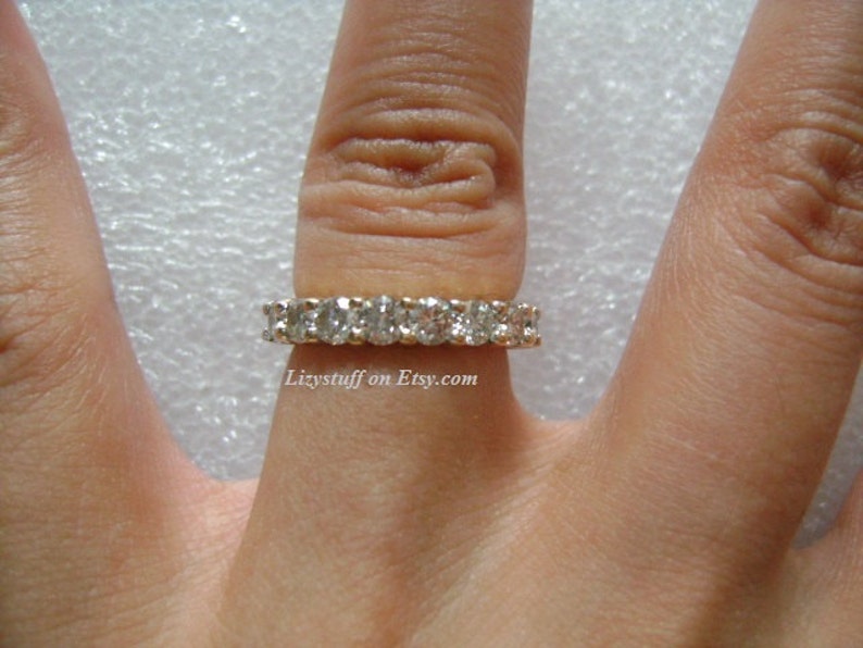 May include: A gold band ring with a row of clear cubic zirconia stones.