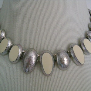 Puede incluir: Un collar de plata con piedras ovaladas blancas. El collar est&aacute; hecho de metal y tiene un acabado texturizado.