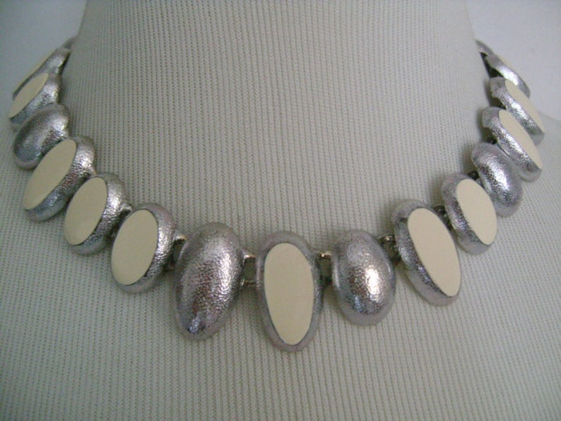Puede incluir: Un collar de plata con piedras ovaladas blancas. El collar est&aacute; hecho de metal y tiene un acabado texturizado.