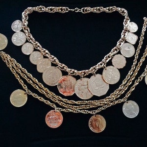 May include: A gold necklace with multiple strands of chain and coin-shaped pendants. The necklace is on a black background.
