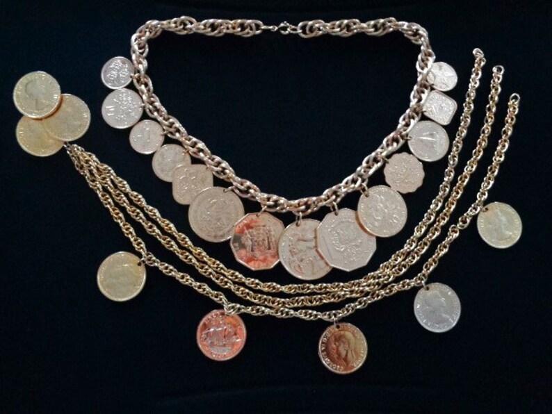 May include: A gold necklace with multiple strands of chain and coin-shaped pendants. The necklace is on a black background.