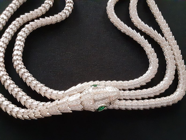 Peut inclure: Un collier en argent avec une cha&icirc;ne en forme de serpent et un pendentif t&ecirc;te de serpent. La t&ecirc;te de serpent est incrust&eacute;e de pierres claires et a des yeux verts.
