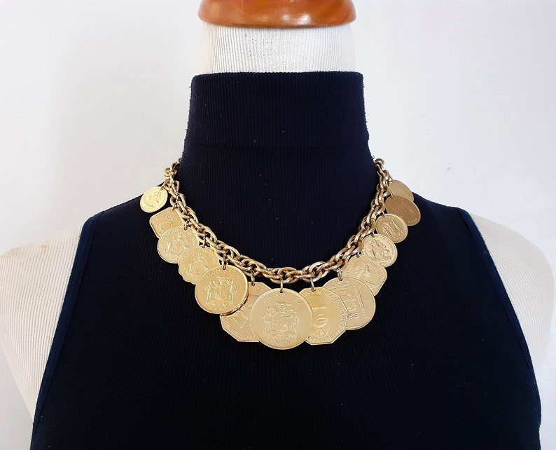May include: A gold chain necklace with multiple gold coin charms. The coins have various designs and are attached to the chain with jump rings.
