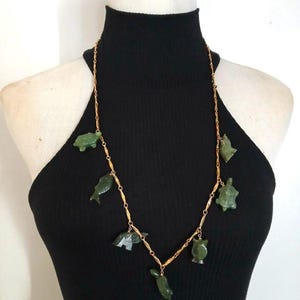 May include: A gold chain necklace with green jade animal charms. The charms include a turtle, fish, owl, and other animals.