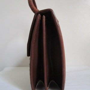 May include: A brown leather handbag with a top handle and a flap closure. The bag has a structured shape and a smooth finish.