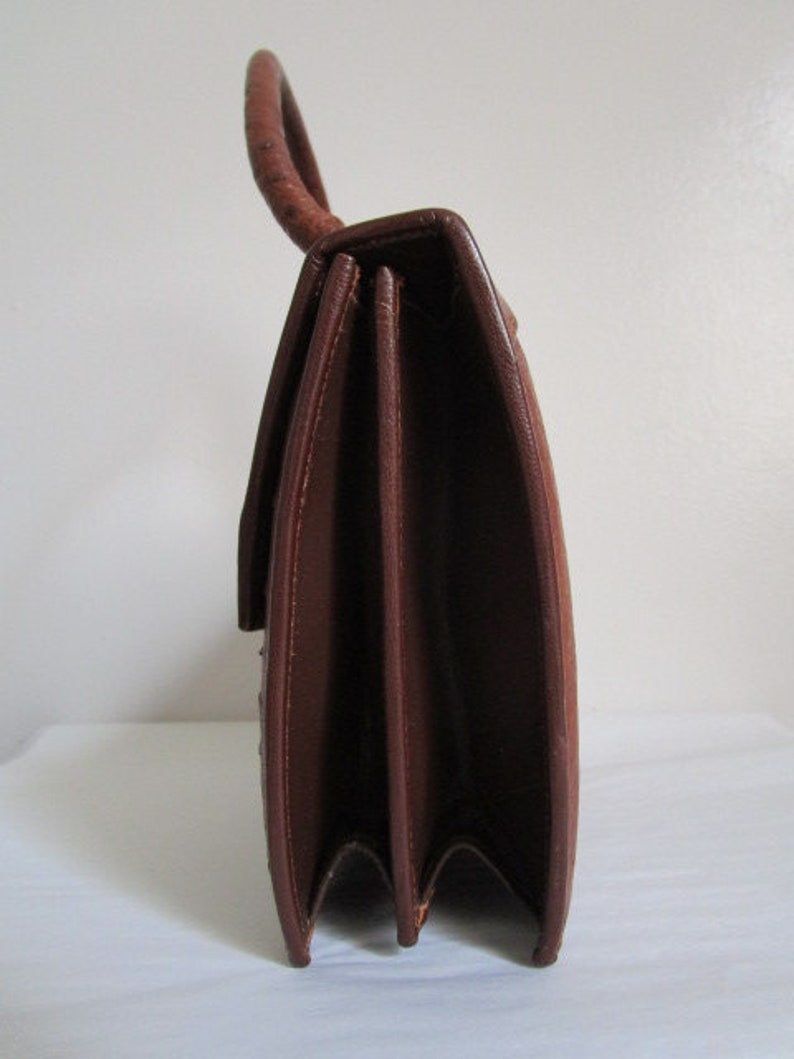 May include: A brown leather handbag with a top handle and a flap closure. The bag has a structured shape and a smooth finish.