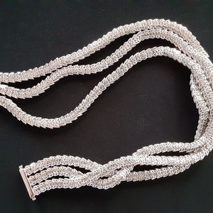 Peut inclure: Un collier en argent avec un design &agrave; trois brins. Chaque brin est compos&eacute; de petits maillons entrelac&eacute;s qui cr&eacute;ent un motif d&eacute;licat et complexe.
