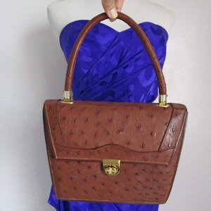May include: A brown ostrich leather handbag with a gold clasp and a top handle.