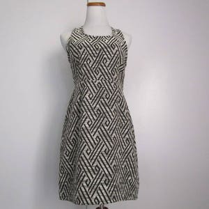 May include: A sleeveless black and white geometric patterned dress with a scoop neck.