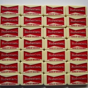 May include: Twenty-eight white dominoes with red lettering. Each domino reads "Budweiser King of Beers".