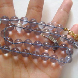 May include: A necklace made of light blue glass beads with a gold clasp.