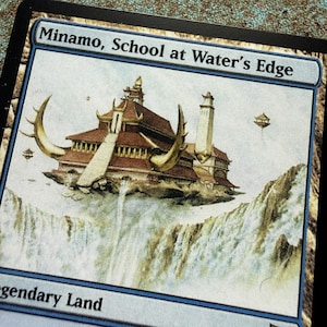 May include: A Magic: The Gathering trading card titled Minamo, School at Water's Edge. The illustration depicts a multi-tiered building with large curved horns, floating above a waterfall. The card frame is light blue with the text Legendary Land.