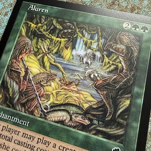 May include: A green Magic: The Gathering trading card titled Aluren featuring an illustration of two figures in a forest setting with various creatures, a waterfall, and text including the word enchantment and a casting cost of two and two green mana.