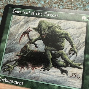 May include: A green Magic: The Gathering trading card titled Survival of the Fittest. The artwork depicts a green goblin-like creature standing over a fallen dark creature, holding a red-tipped pickaxe. The card frame is green with white text.