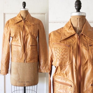 May include: A brown leather jacket with a woven design on the pockets and a zipper closure. The jacket has a collar and long sleeves.