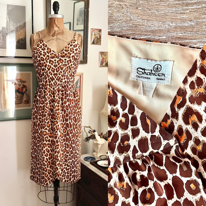 May include: A vintage leopard print dress with spaghetti straps and a V-neck. The dress is displayed on a mannequin. The fabric features brown and orange spots on a cream background. The label reads "Shaheen California Hawaii."