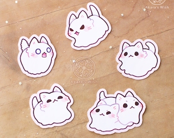 May include: Five white cat stickers with different expressions. The stickers are on a wooden surface. The stickers are all different sizes and shapes. The stickers are all cute and adorable.