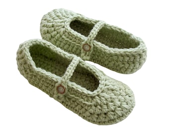May include: A pair of light green crocheted slippers with a button detail. The slippers have a strap that goes over the foot.