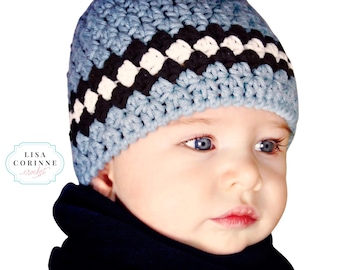 Può includere: Un bambino che indossa un cappello all'uncinetto blu e bianco con una striscia nera. Il cappello ha un motivo a scacchi.