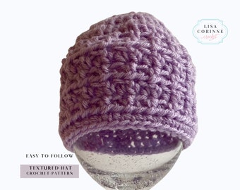 May include: A purple crocheted hat with a textured stitch pattern. The hat is displayed on a clear glass surface. The text "EASY TO FOLLOW TEXTURED HAT CROCHET PATTERN" is below the hat. The text "LISA CORINNE crochet" is in the upper right corner of the image.