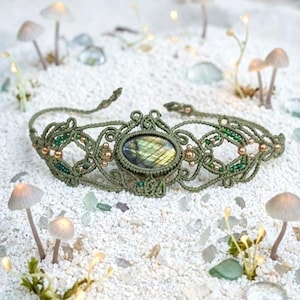 Peut inclure: Un bracelet en macramé vert olive doté d'une pierre centrale ovale en labradorite aux reflets irisés. Le design complexe en cordon noué est agrémenté de petites perles métalliques et de minuscules perles de rocaille vertes.