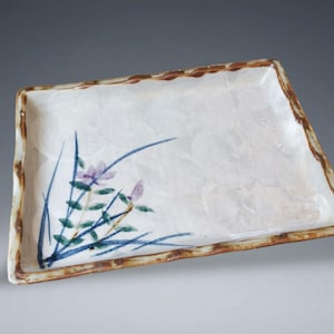 May include: A set of three ceramic mugs with a speckled, matte finish. The mugs are in shades of cream, light gray, and dark gray. Each mug has a simple, minimalist design and a rounded handle.