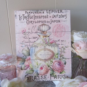 May include: A vintage-style pink and white sign with a floral design and the text "PARFUMERIE L. PIVER Le TreFLE Incarnat * LAIT D'IRIS CORYLOPSIS DU JAPON GRASSE PARIS"