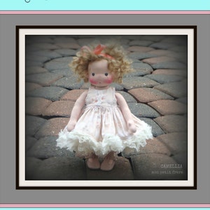 May include: A complete pattern and instructions to make a 9-inch or 12-inch petite Fleur doll. The doll is wearing a pink dress with a white lace trim and has curly blonde hair. The doll is sitting on a brick patio.