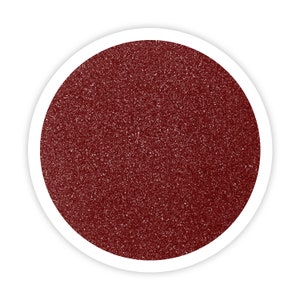 May include: A close-up of a round container filled with fine, dark red glitter.