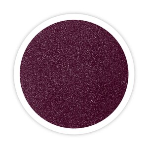 May include: A close-up of a round container filled with dark purple glitter.