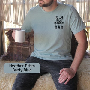 May include: A light blue t-shirt with a black graphic of a French Bulldog peeking over the top of the text "Frenchie Dad".