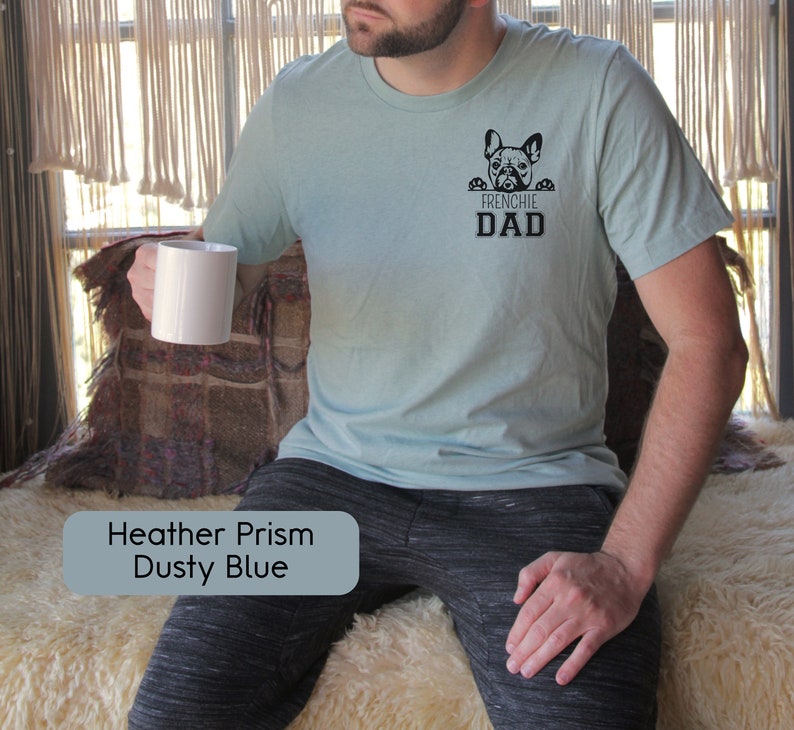 May include: A light blue t-shirt with a black graphic of a French Bulldog peeking over the top of the text "Frenchie Dad".