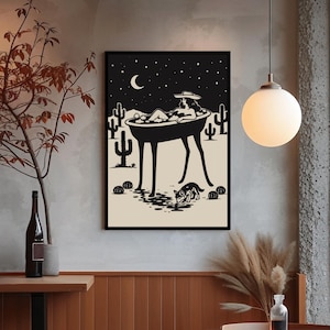 May include: Black and white art print depicting a person relaxing in a bathtub under a starry night sky. The artwork features cacti, a crescent moon, and a dog drinking water. The print is framed in a black border.