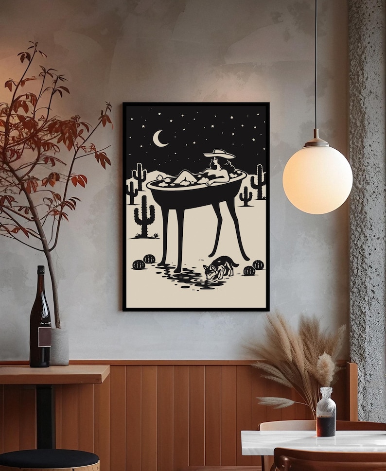 May include: Black and white art print depicting a person relaxing in a bathtub under a starry night sky. The artwork features cacti, a crescent moon, and a dog drinking water. The print is framed in a black border.