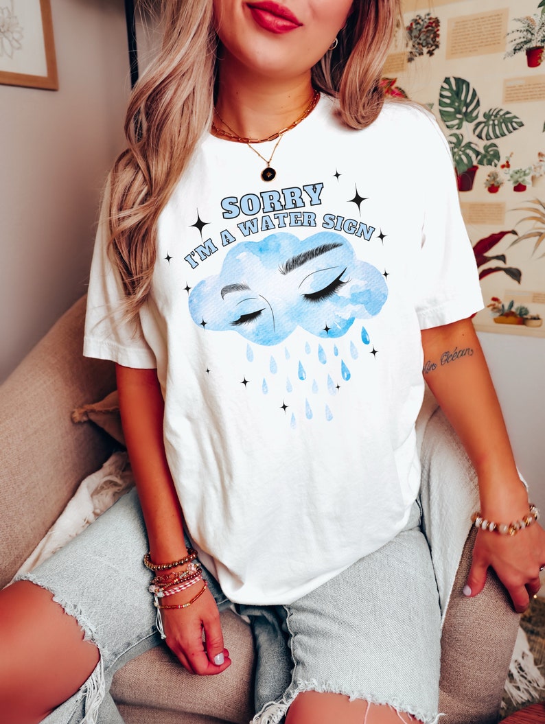 May include: White t-shirt with a blue cloud graphic and the text "Sorry I'm a water sign".