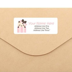 May include: A brown envelope with a white label featuring a cartoon cat wearing a pink bow. The label says "Your Name Here" and includes space for an address.