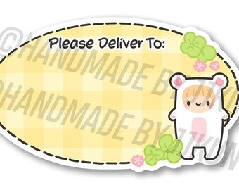 May include: A yellow oval sticker with a gingham pattern and the text "Please Deliver To:". A cartoon character wearing a white bear costume with pink accents is on the right side of the sticker. The sticker is 2 inches in diameter.