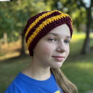 Puede incluir: Una diadema de ganchillo a rayas burdeos y doradas. Este accesorio hecho a mano es una cubierta para la cabeza ancha, suave y cómoda. La diadema es un artículo elegante y práctico para mantener el cabello fuera de la cara.