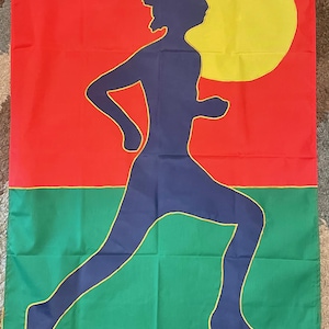 May include: A green, yellow, and red flag with a silhouette of a person running. The person is blue and outlined in yellow. The flag has a yellow sun in the upper right corner.
