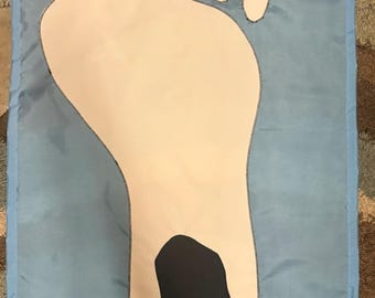 May include: A rectangular light blue fabric flag featuring a large, centred white footprint graphic. The footprint design includes five small white ovals representing toes and a prominent black, irregular shape positioned in the centre of the sole.